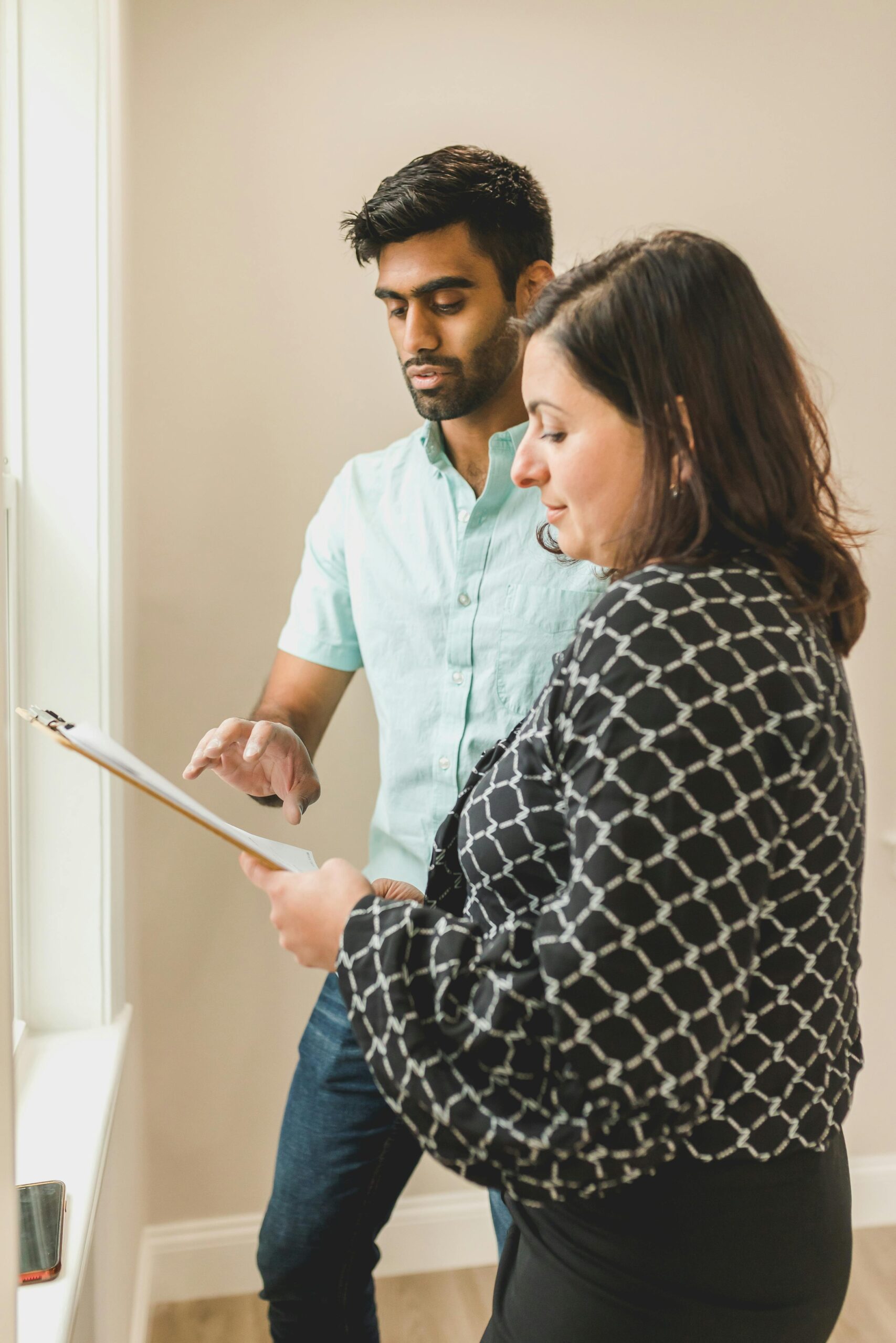 Two colleagues reviewing documents on a clipboard in an office setting.